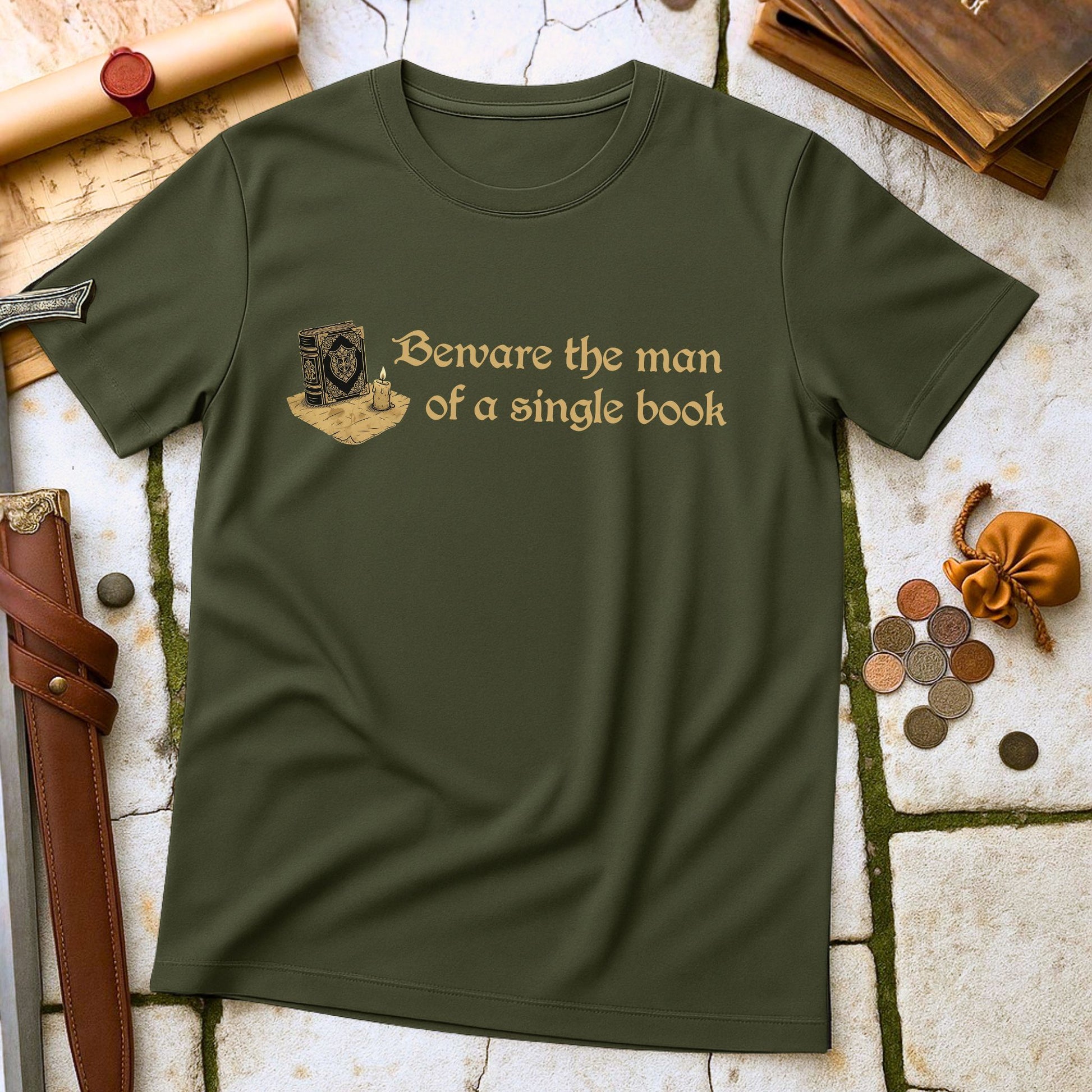 Military Green t-shirt with text and graphic on a stone surface with books and coins.