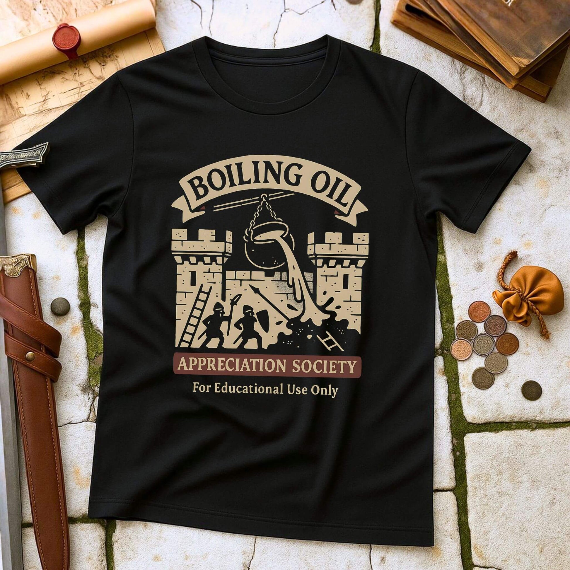 Black t-shirt with 'Boiling Oil Appreciation Society' graphic on a stone surface with historical props.