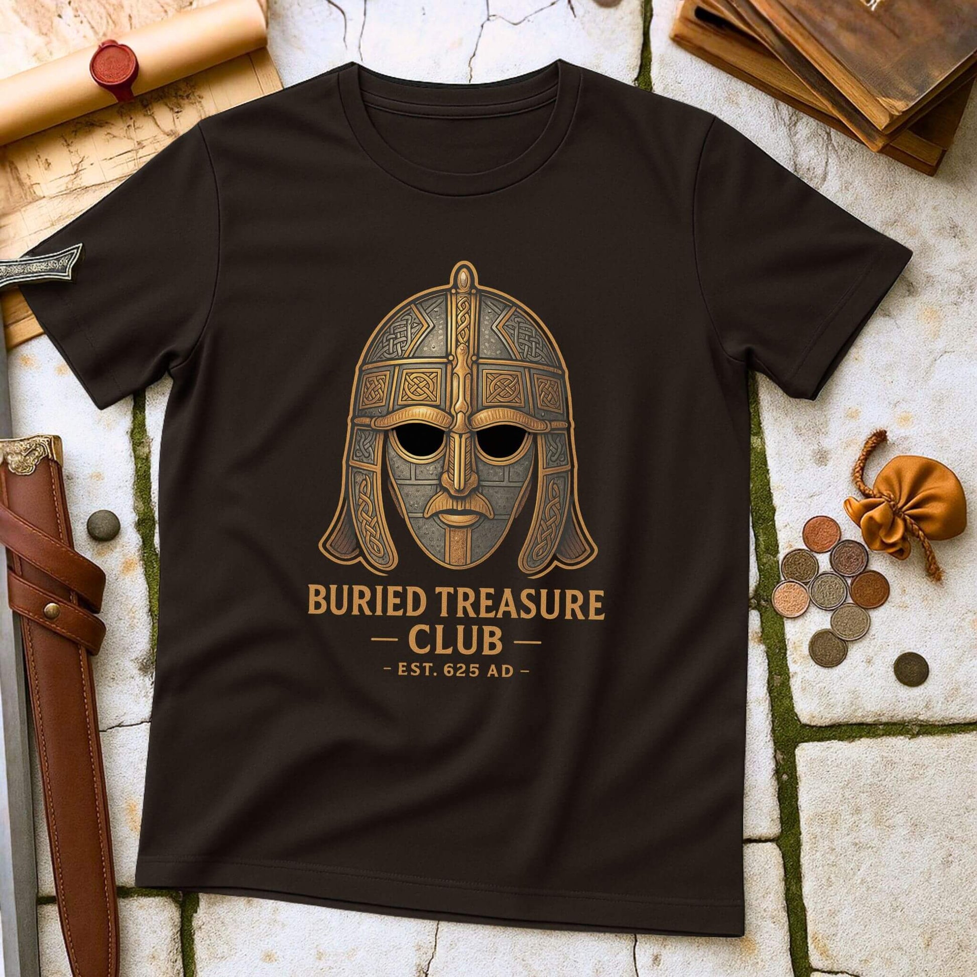 Dark Chocolate t-shirt with a Sutton Hoo helmet  graphic and 'Buried Treasure Club EST.625 AD' text on a stone surface