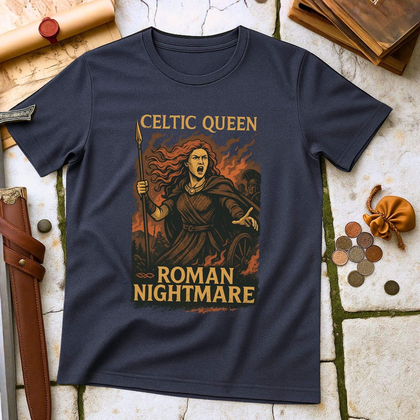 Navy blue t-shirt with 'Celtic Queen, Roman Nightmare' design on a stone surface with historical props.