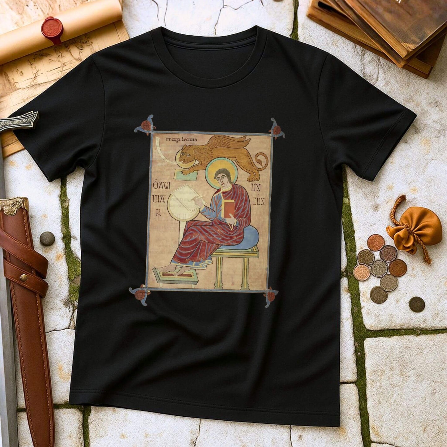 Black t-shirt with an iIlluminated Manuscript graphic on a stone surface.