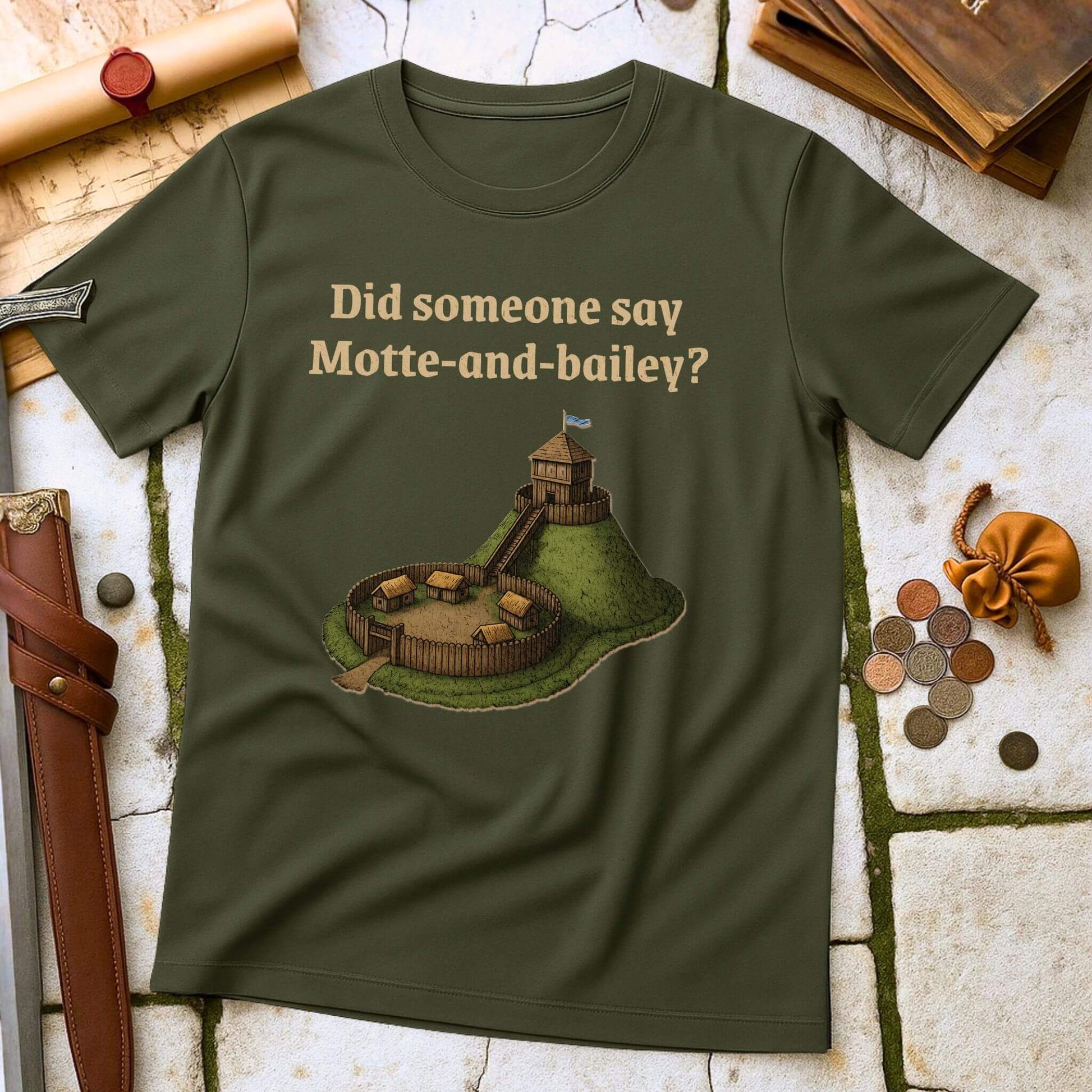 Military Green t-shirt with a graphic and text " Did someone say Motte and Bailey" on a stone surface with props.