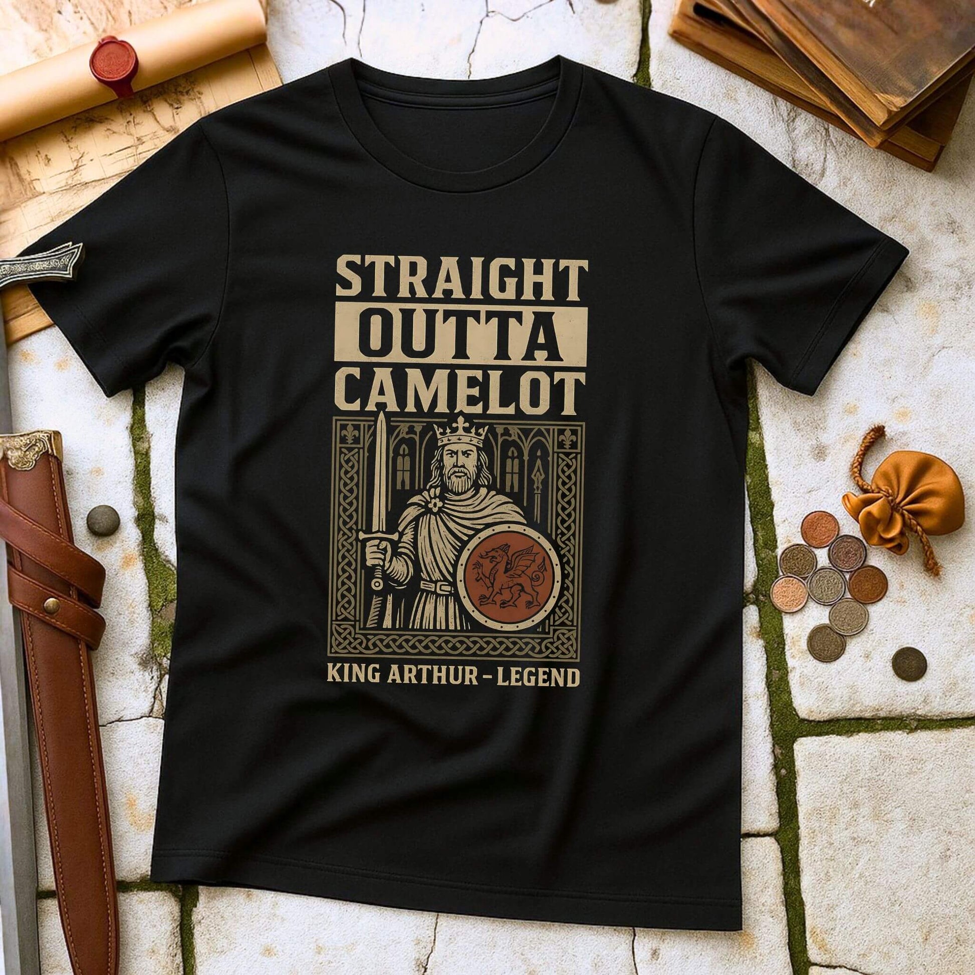 Black t-shirt with 'Straight Outta Camelot' graphic on a stone surface with props.
