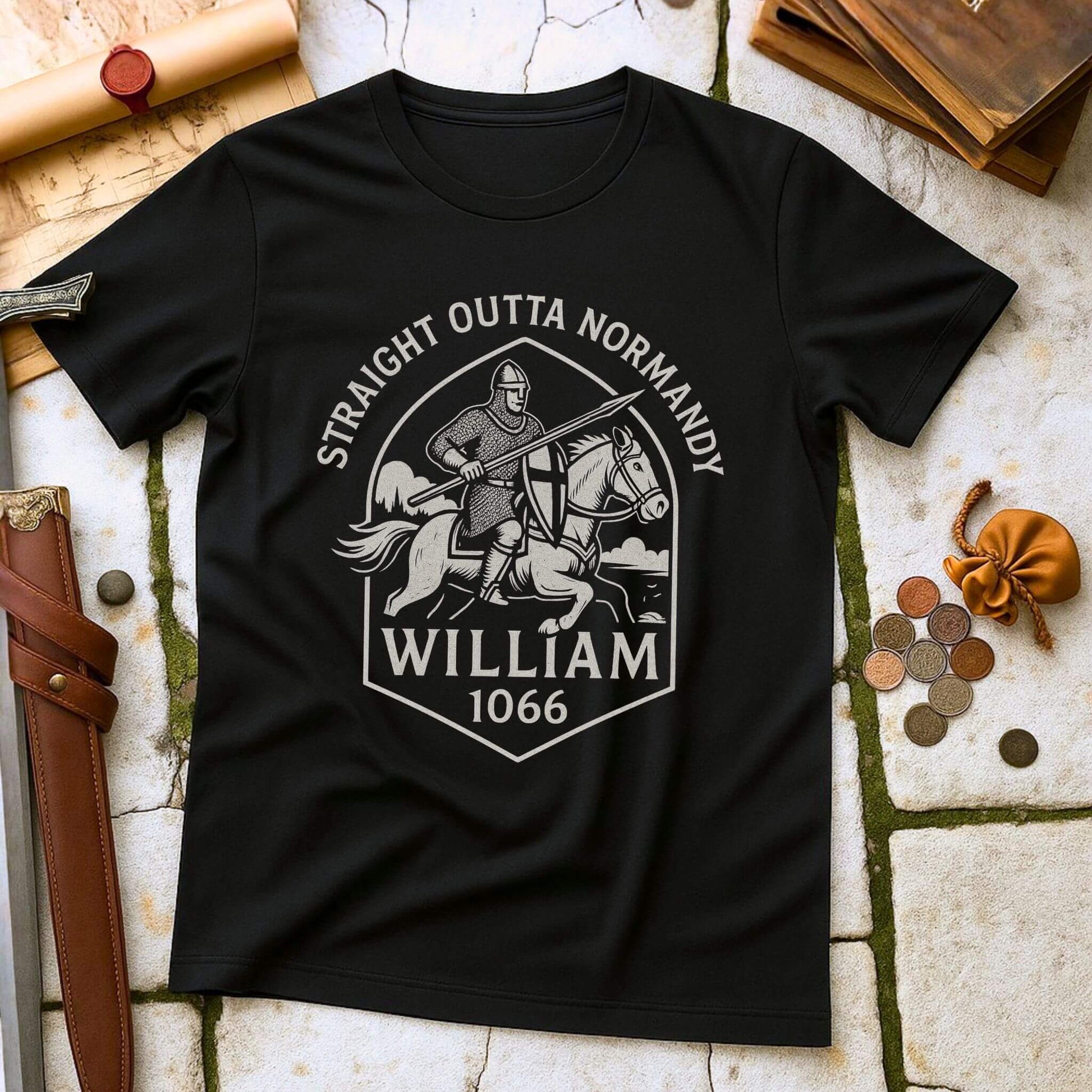 Black t-shirt with a graphic design of a knight with printed text that says " Straight outta Normandy WIlliam 1066"  on a stone surface with historical props.