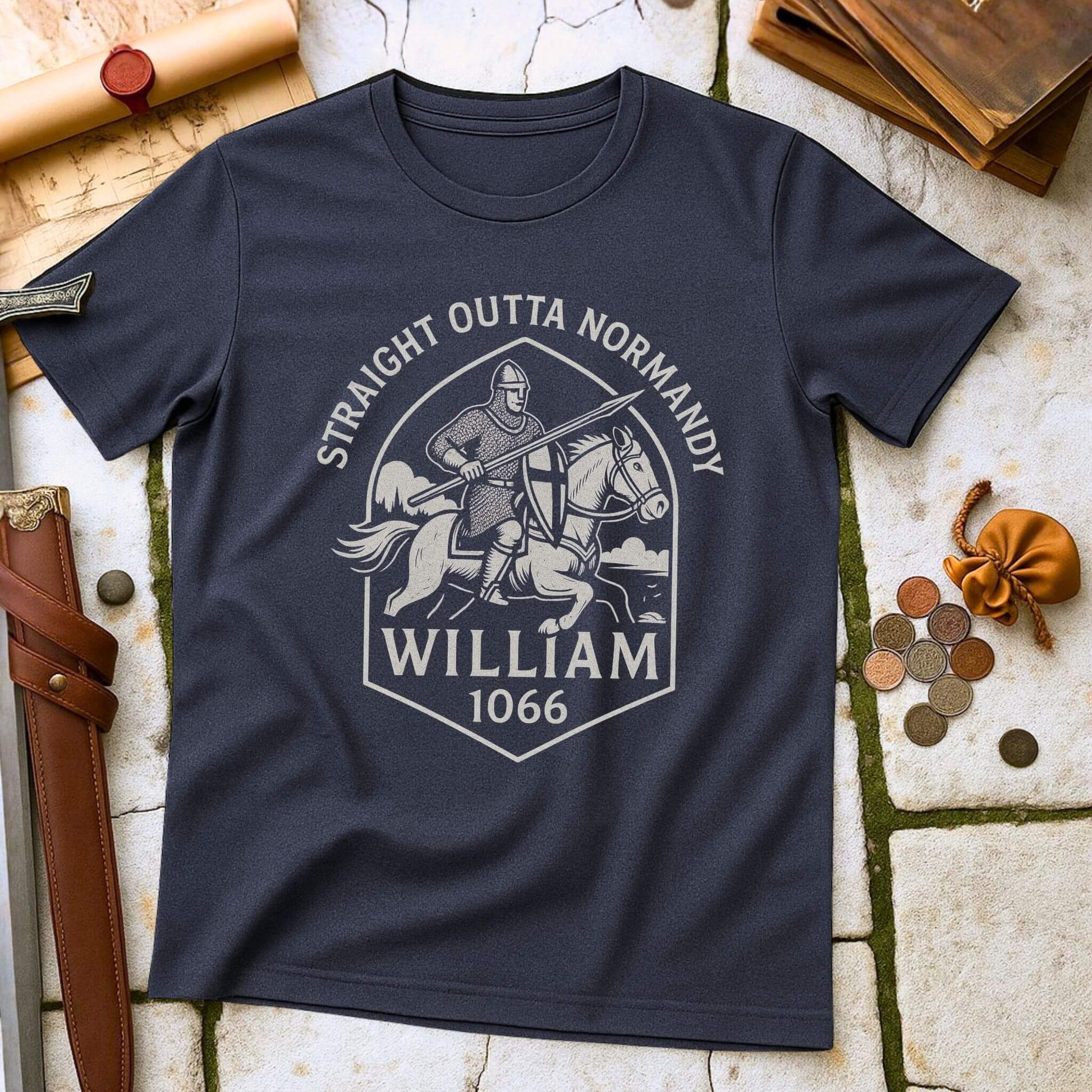 Heather Navy t-shirt with a graphic design of a knight with printed text that says " Straight outta Normandy WIlliam 1066"  on a stone surface with historical props.