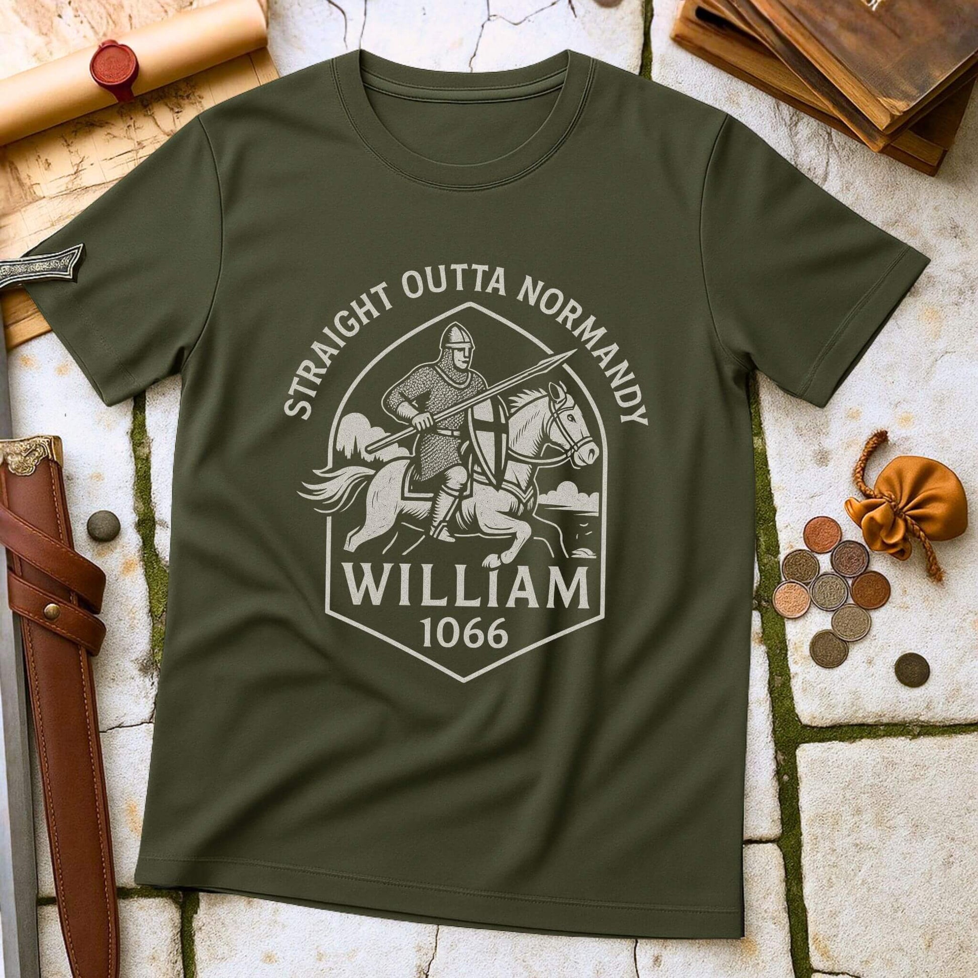 Military Green t-shirt with a graphic design of a knight with printed text that says " Straight outta Normandy WIlliam 1066"  on a stone surface with historical props.